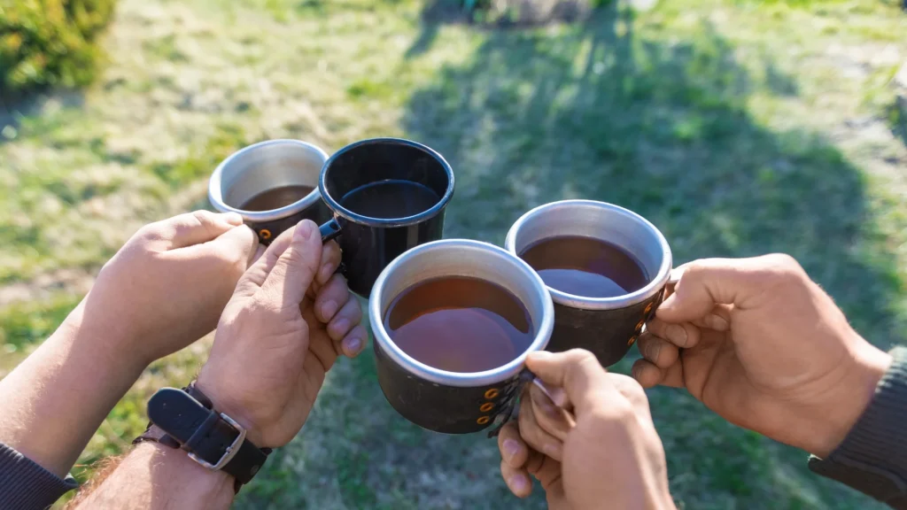 Four friends enjoying a warm cup of tea outside, surrounded by nature and sharing laughter. Health Benefits of Tea
