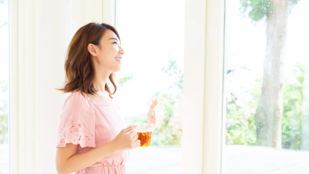 A woman enjoying a cup of tea by the window, taking in the view and savoring the moment.