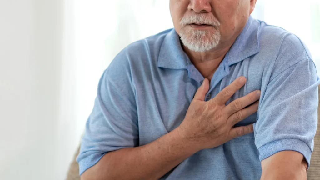 A man clutching his chest in pain, showing symptoms of a heart attack.