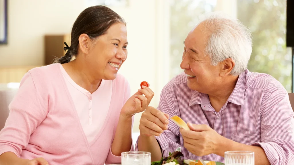 An older couple enjoying a meal together at a table, savoring delicious food and each other's company.