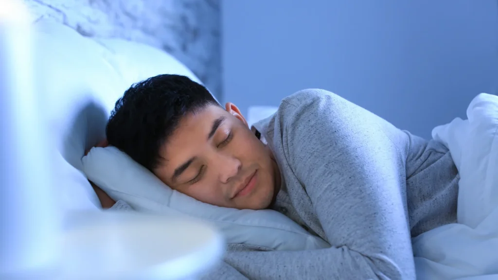 A man peacefully sleeping in bed with his eyes closed.