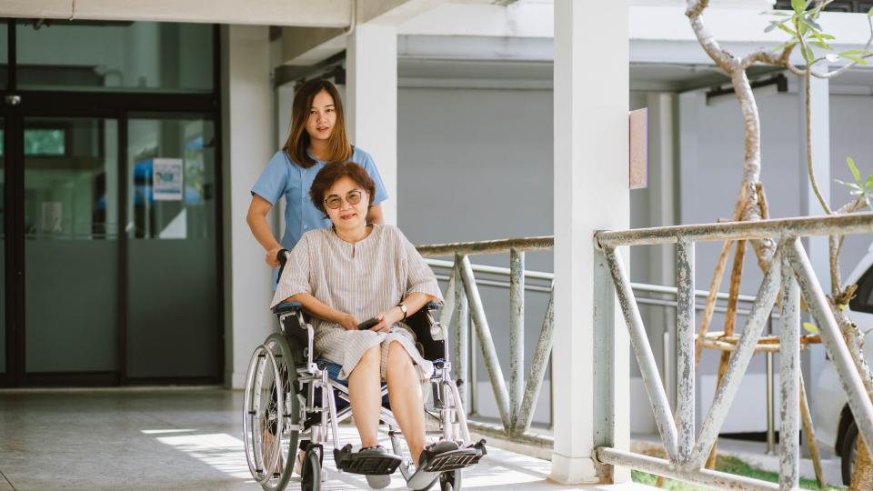 A woman in a wheelchair being assisted by a caring nurse.