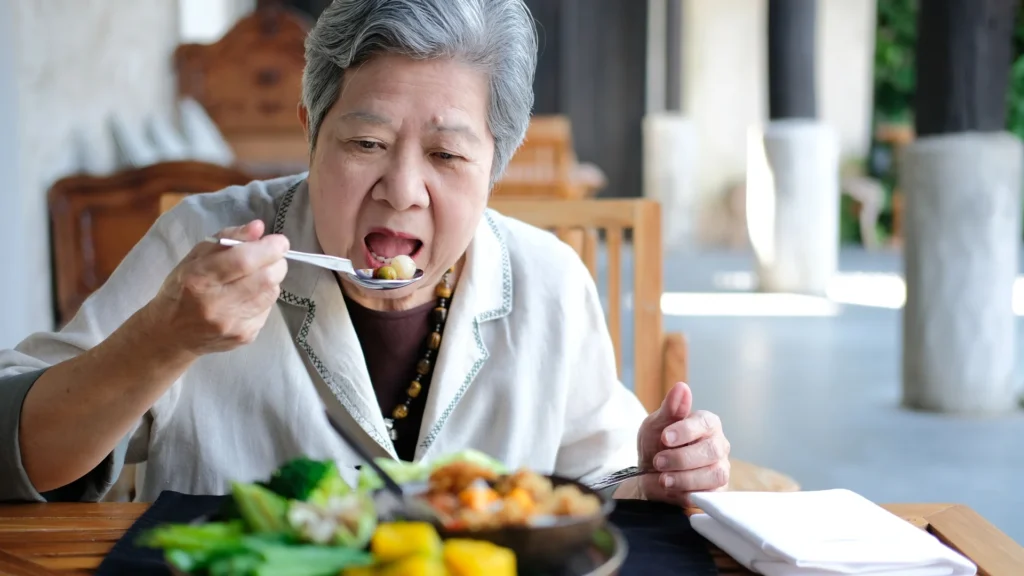 Elderly woman enjoying a meal with utensils