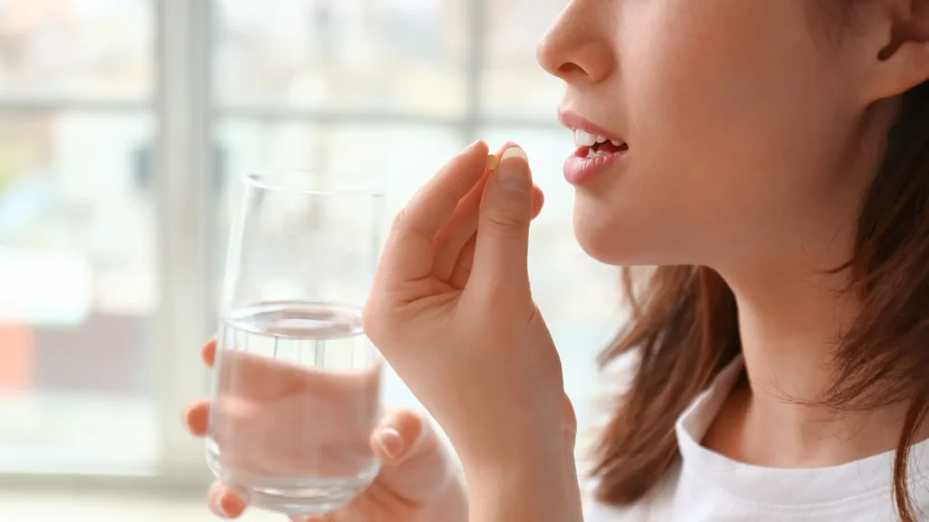A woman holding a pill in her mouth.