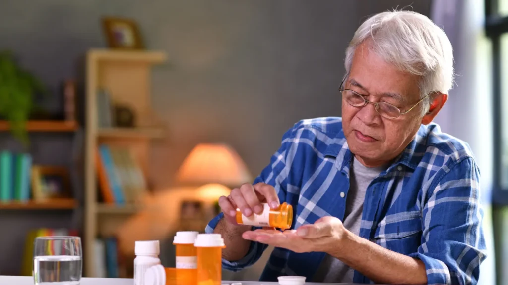 Elderly man holding a pill bottle, about to take medication.