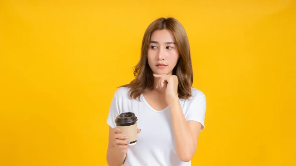 Young woman smiling, holding coffee cup.