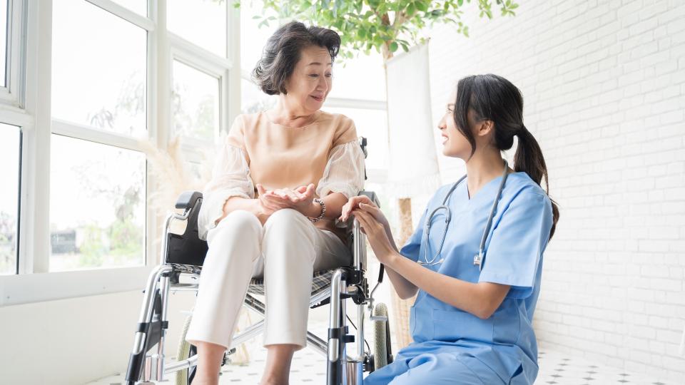 A woman in a wheelchair being assisted by a nurse.