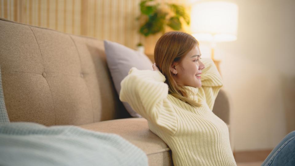 A woman sitting on a couch, smiling warmly.