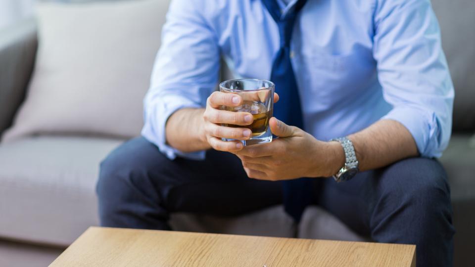 Businessman relaxing on couch with glass of whiskey in hand.