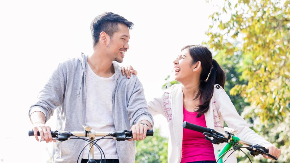 A couple enjoying a bike ride together, smiling and pedaling side by side on their bicycles.