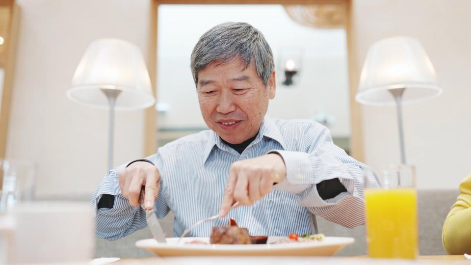 An elderly man enjoying a meal at a restaurant, savoring the flavors and ambiance of the dining experience. High Blood Pressure.