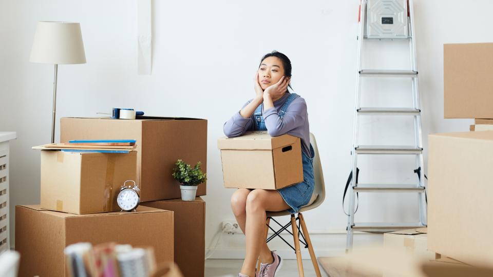 A woman sitting on a chair surrounded by boxes. Sleep Deprivation