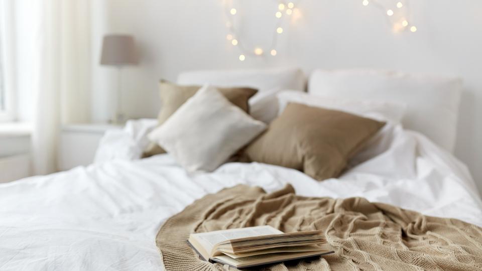 A cozy bed with a neatly folded blanket and a book resting on it, inviting relaxation and leisure.