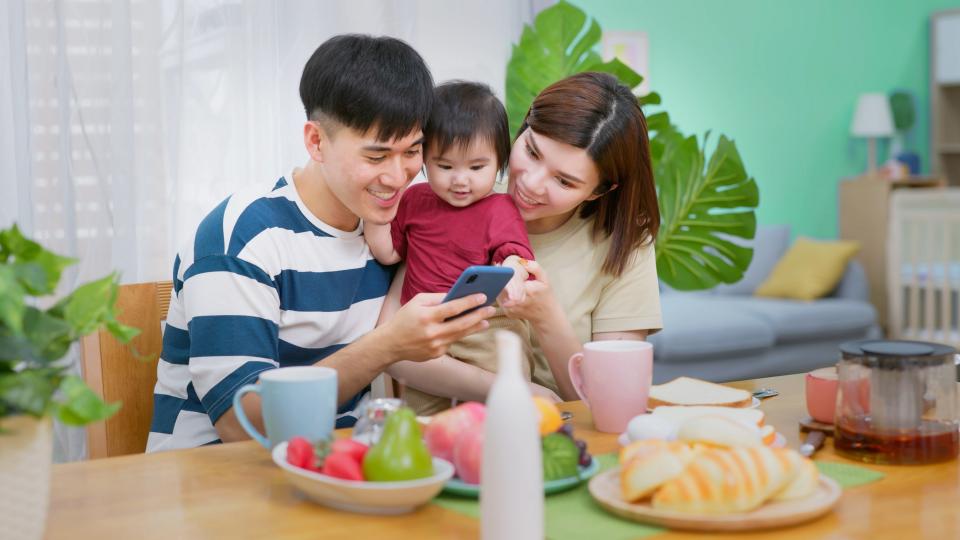Family enjoying breakfast together while using smartphone.