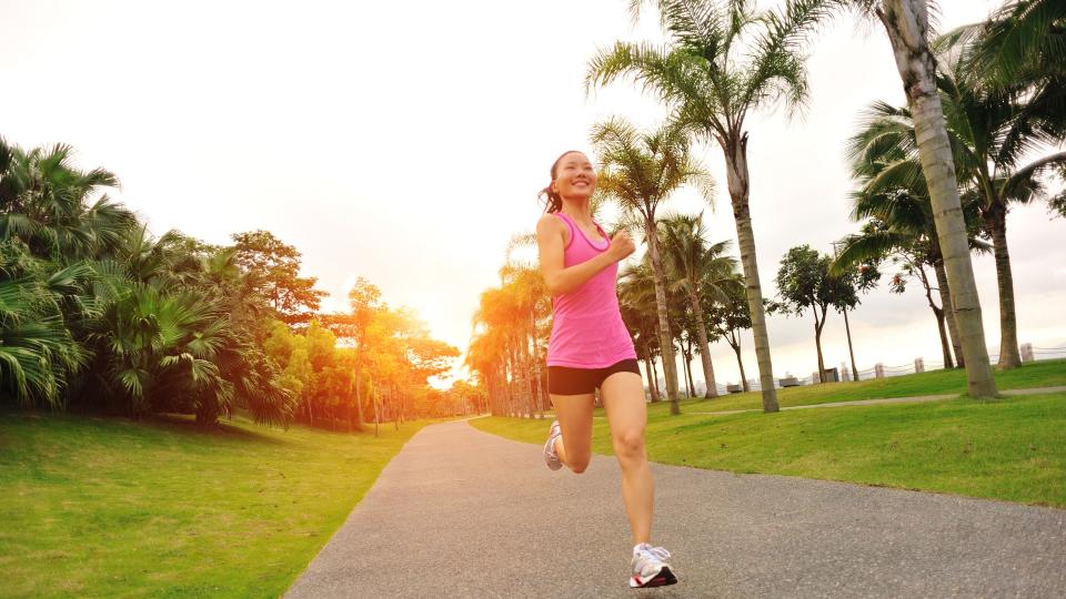 A woman jogging in a park during sunset.