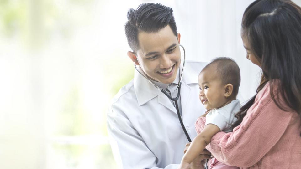 A doctor joyfully cradles a baby in their arms, radiating warmth and care.
