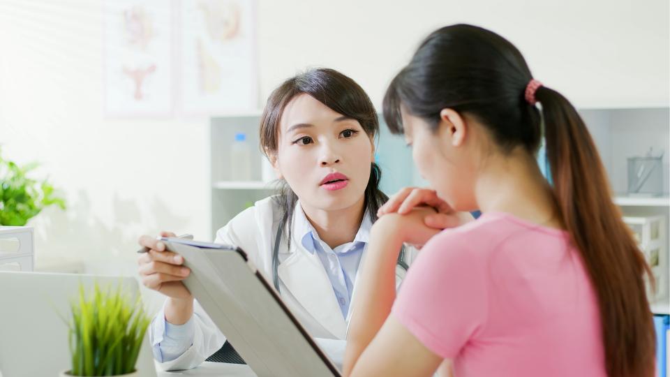 A woman discussing her health concerns with a doctor in a professional setting. Rubella.