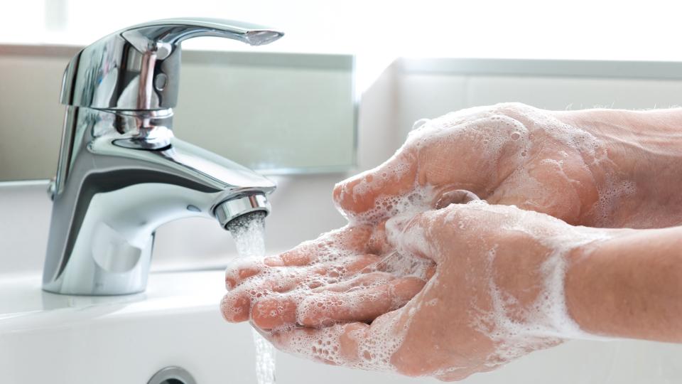 A person washing hands with soap and water, promoting good hygiene and preventing the spread of germs.