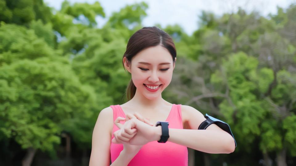 A woman happily smiles while wearing a smart watch.