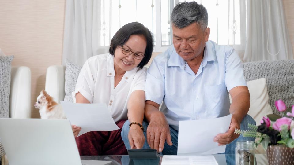 Elderly couple reviewing financial records on laptop and paper. Senior Health