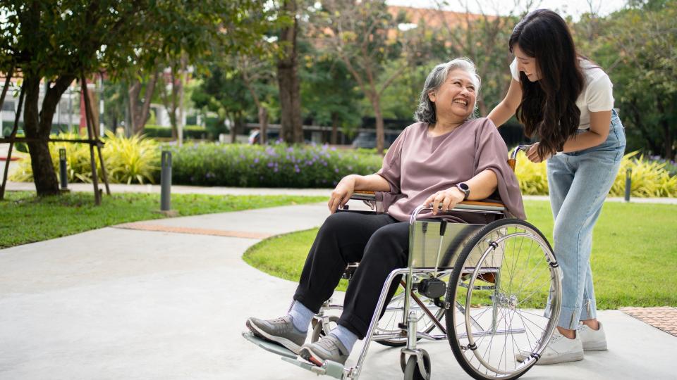 A woman assisting elderly woman in wheelchair.