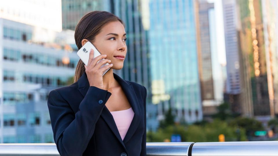 A professional woman in a business suit having a phone conversation.