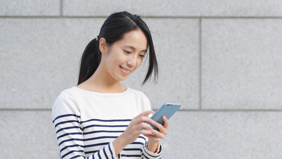 A woman smiling while using smartphone.