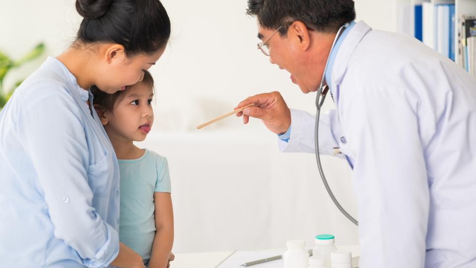 Doctor using stethoscope to examine child in clinic.