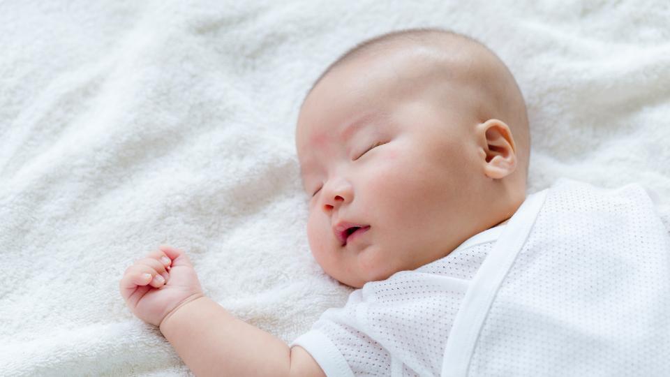 A peaceful baby sleeping on a soft white blanket. Baby Bedtime Routine