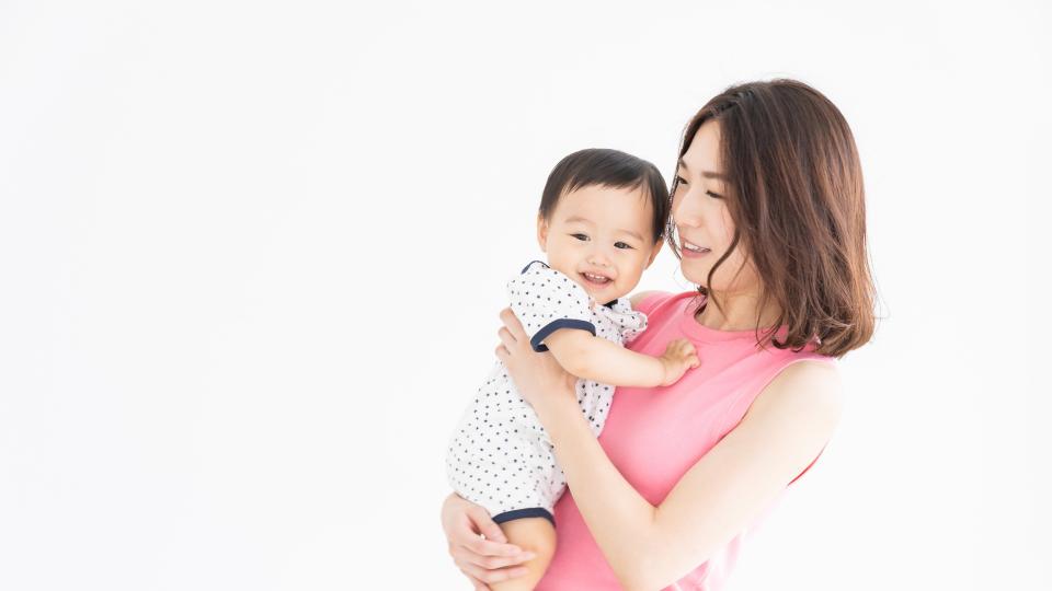 A mother lovingly cradling her baby in front of a white background.