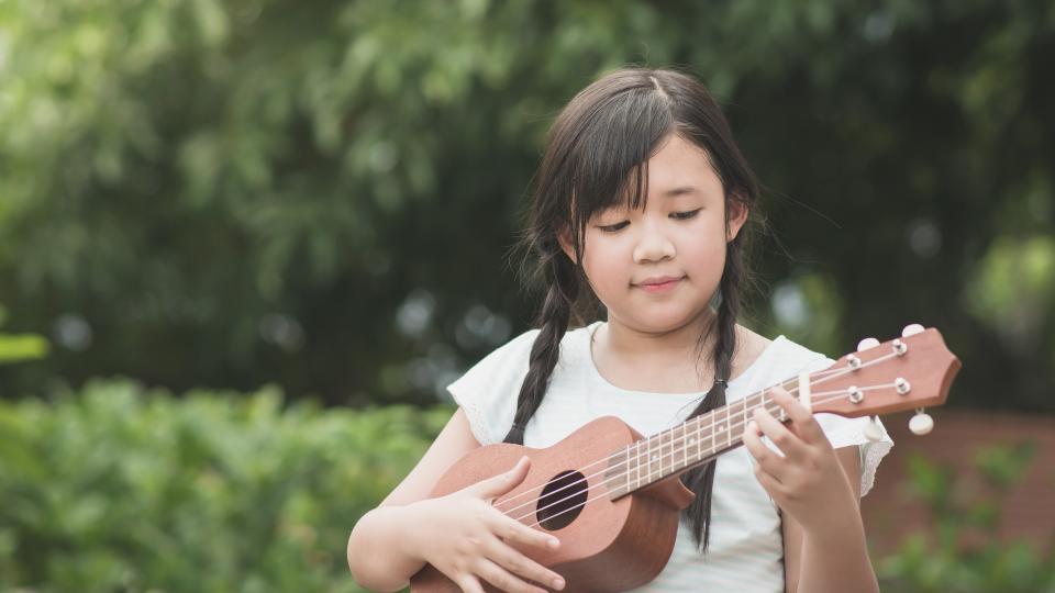 A child playing with a ukulele.
