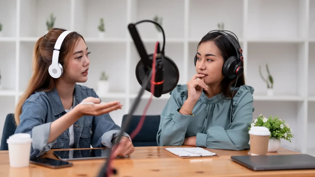 Two women in headphones having a conversation. Best Podcasts for Medical Students