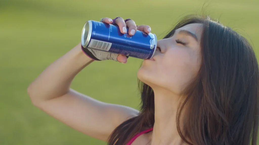 A woman enjoying a refreshing soda from a can, quenching her thirst with a delightful beverage.