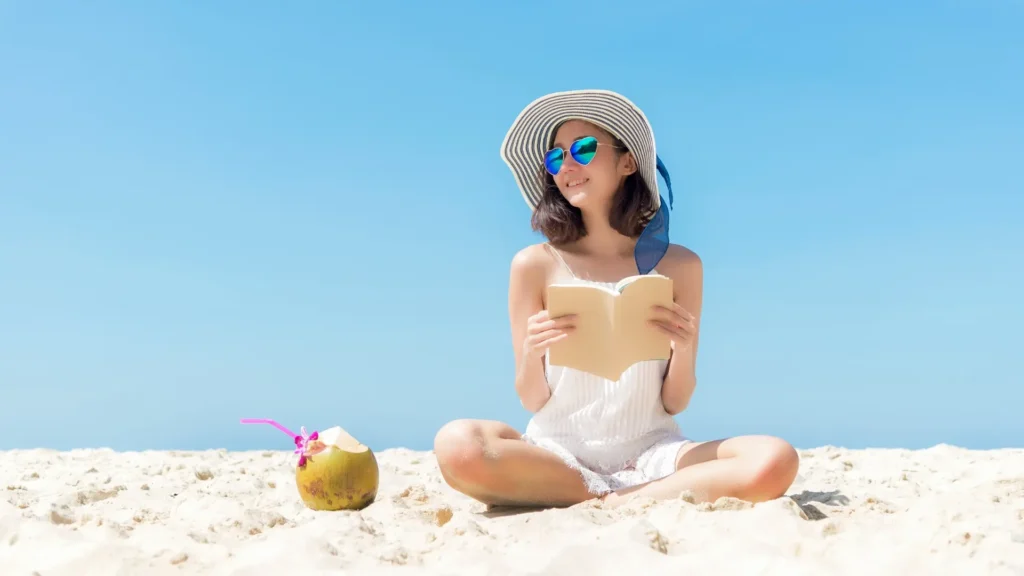 A woman reading a book on the beach. 