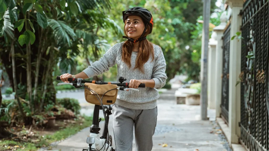 Woman wearing helmet rides bike on sunny day.