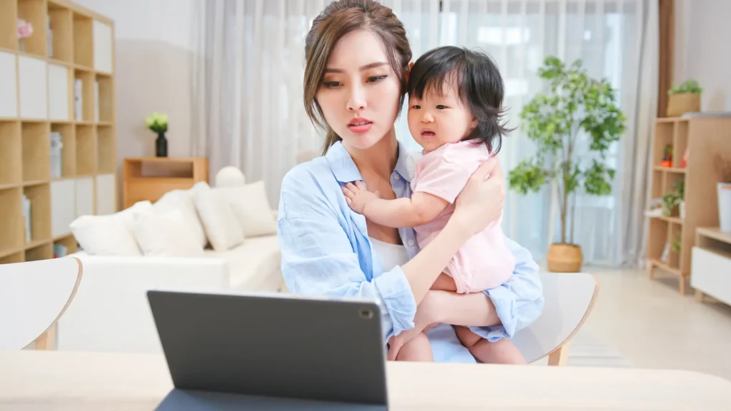 A multitasking mom with her adorable baby, working on her laptop.