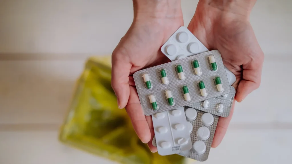 A person holding a pack of pills, ready to take medication for health purposes.