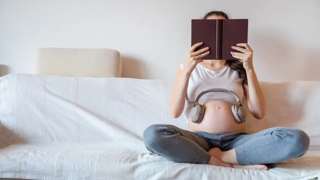 A pregnant lady reading a book.