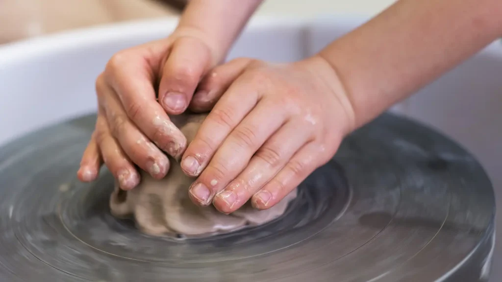 Sensory Stimulation. A potter shaping clay on a spinning wheel, creating a ceramic pot.