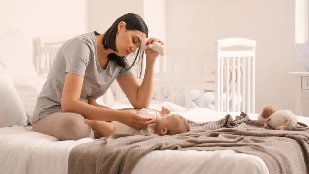 A mother gently brushes her baby's hair while sitting on a bed. The bond between them is evident in this tender moment.
