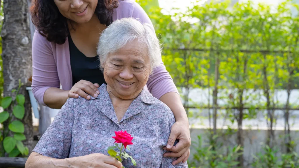 7 stages of Vascular Dementia. A woman gently offers a flower to elderly woman, showing love and care.