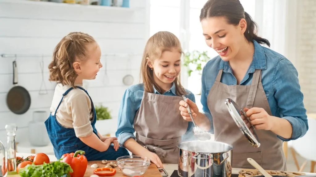 A woman and two children cooking together in a cozy kitchen.