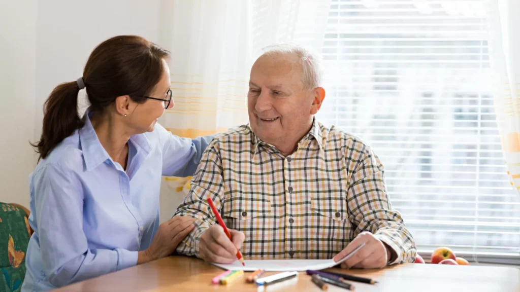 A woman assisting an elderly man with writing, showing care and support.