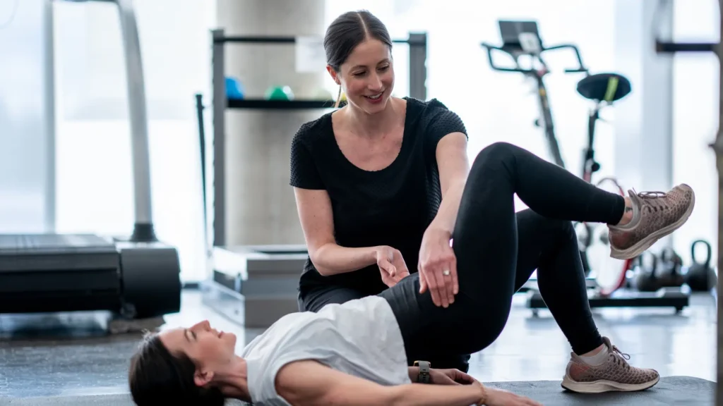 Woman doing leg exercise with trainer in gym.