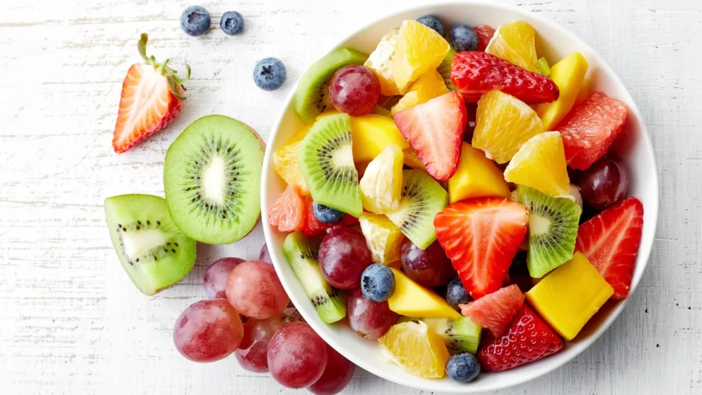 A bowl of assorted fruit on a wooden table. Snacks to eat while Detoxing