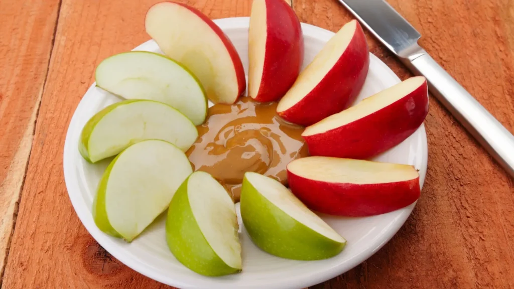 Sliced apples and peanut butter on a white plate, a nutritious and delicious combination.