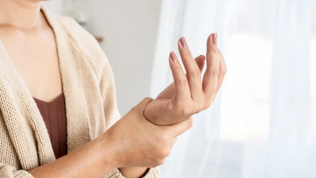 A woman gently touching her wrist, showing care and concern. Postpartum Arthritis