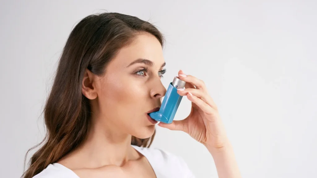 A woman using an asthma inhaler to manage her respiratory condition.