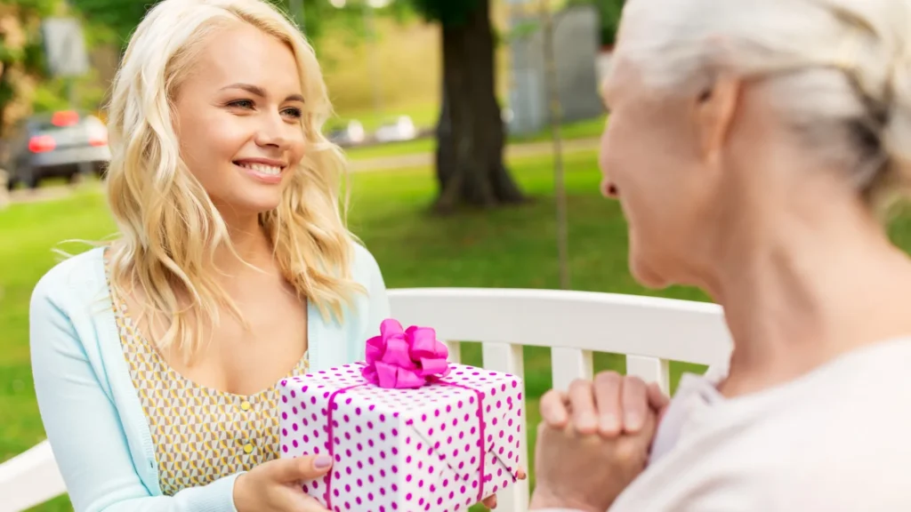 Young woman presenting a gift to elderly woman, showing love and appreciation.