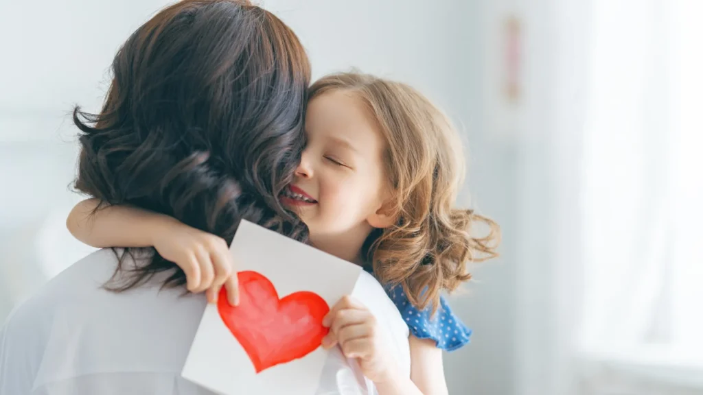 A woman holding a child with a heart on a piece of paper, symbolizing love and care.